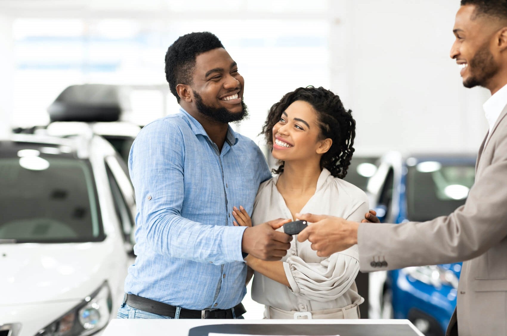Sales consultant handing keys to customer in dealer showroom